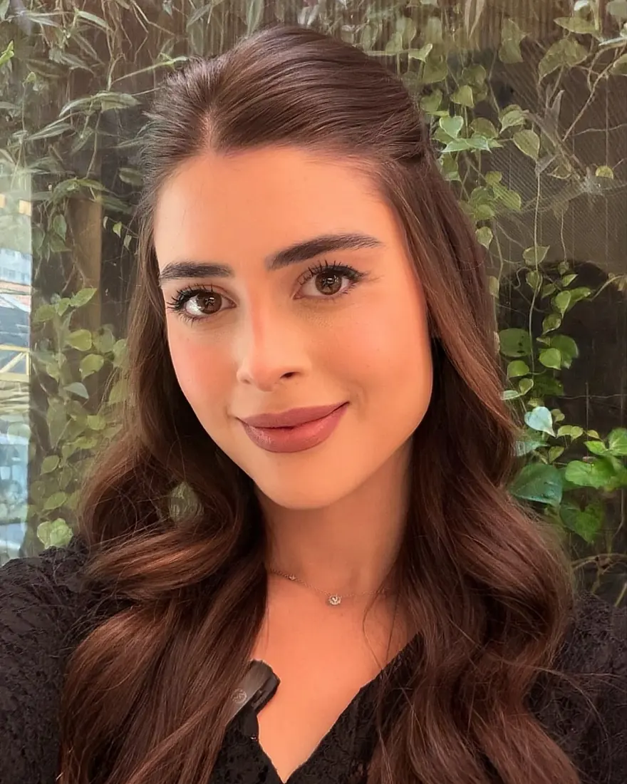 Stephanie de blusa preta de renda, com plantas ao fundo